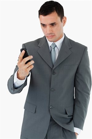 simsearch:400-05718346,k - Serious looking businessman looking at his cellphone against a white background Foto de stock - Super Valor sin royalties y Suscripción, Código: 400-05718346