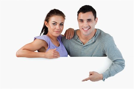 simsearch:400-05718227,k - Young couple presenting advertisement against a white background Stock Photo - Budget Royalty-Free & Subscription, Code: 400-05718725