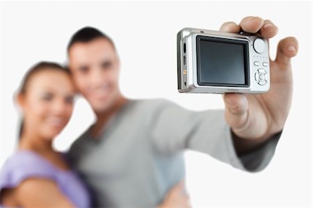 simsearch:400-04151970,k - Camera being used to take a picture of young couple against a white background Fotografie stock - Microstock e Abbonamento, Codice: 400-05718761