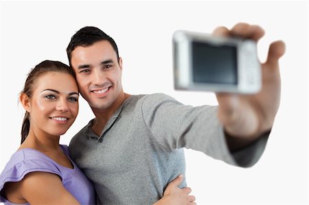 simsearch:400-04151970,k - Young couple taking photograph of themselves against a white background Fotografie stock - Microstock e Abbonamento, Codice: 400-05718762