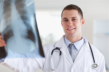 simsearch:400-05710928,k - Smiling young doctor looking at x-ray in his hands Stockbilder - Microstock & Abonnement, Bildnummer: 400-05710425