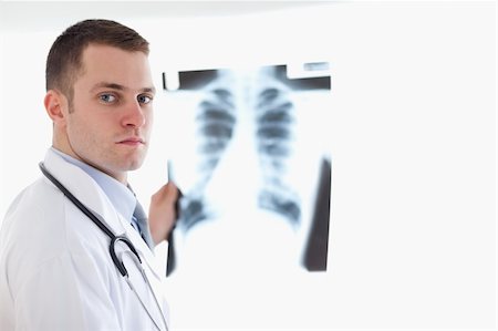 simsearch:400-05710928,k - Serious looking doctor holding x-ray image against light Stockbilder - Microstock & Abonnement, Bildnummer: 400-05710441