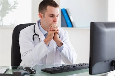 simsearch:400-05710928,k - Thinking young doctor looking at his screen Stockbilder - Microstock & Abonnement, Bildnummer: 400-05710458