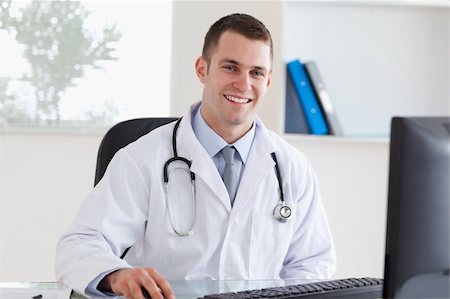 simsearch:400-05710928,k - Smiling young doctor on his computer Stockbilder - Microstock & Abonnement, Bildnummer: 400-05710452