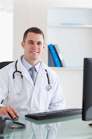 simsearch:400-05710928,k - Smiling young doctor sitting on his computer Stockbilder - Microstock & Abonnement, Bildnummer: 400-05710453