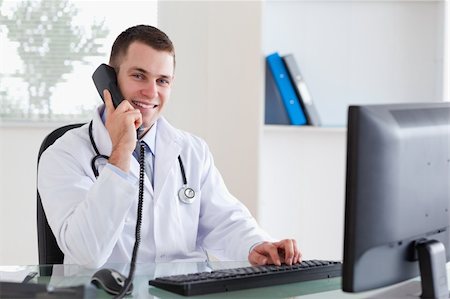 simsearch:400-05710928,k - Smiling young doctor on the telephone Stockbilder - Microstock & Abonnement, Bildnummer: 400-05710918