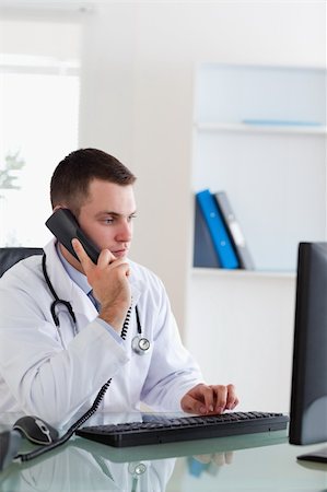 simsearch:400-05710928,k - Doctor on the telephone while looking at the computer screen Stockbilder - Microstock & Abonnement, Bildnummer: 400-05710920