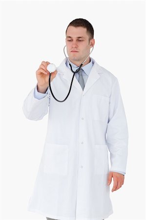 simsearch:400-05710928,k - Doctor looking at stethoscope while using it on white background Stockbilder - Microstock & Abonnement, Bildnummer: 400-05710959