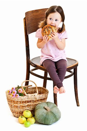 Cute little girl with ponytails eating cookie. Isolated on white Stock Photo - Budget Royalty-Free & Subscription, Code: 400-05727682