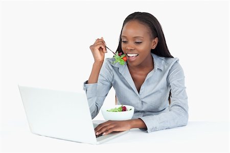 Businesswoman working with a laptop while eating a salad against a white background Stock Photo - Budget Royalty-Free & Subscription, Code: 400-05729264