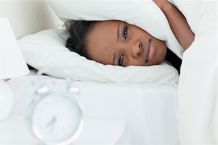 simsearch:6109-06194402,k - Woman covering her ears while her alarm clock is ringing in her bedroom Stock Photo - Budget Royalty-Free & Subscription, Code: 400-05729378