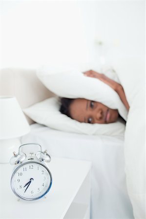 simsearch:6109-06194408,k - Portrait of a tired woman covering her ears while her alarm clock is ringing in her bedroom Stockbilder - Microstock & Abonnement, Bildnummer: 400-05729384