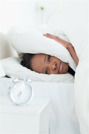 simsearch:6109-06194890,k - Portrait of a woman covering her ears while her alarm clock is ringing in her bedroom Stockbilder - Microstock & Abonnement, Bildnummer: 400-05729382
