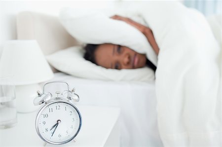 simsearch:6109-06194890,k - Exhausted woman covering her ears while her alarm clock is ringing in her bedroom Stockbilder - Microstock & Abonnement, Bildnummer: 400-05729383