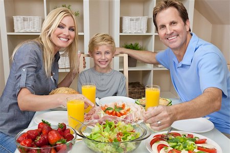 An attractive happy, smiling family of mother, father and son eating salad and healthy food at a dining table Stock Photo - Budget Royalty-Free & Subscription, Code: 400-05721403