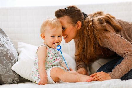 simsearch:400-05899075,k - Adorable baby with soother and young mother playing on divan at home Fotografie stock - Microstock e Abbonamento, Codice: 400-05723079