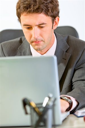 simsearch:400-04188055,k - Portrait of modern businessman sitting at office desk and working on laptop Stock Photo - Budget Royalty-Free & Subscription, Code: 400-05735106