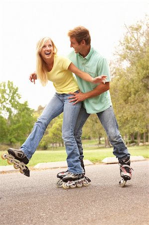 Couple Wearing In Line Skates In Park Foto de stock - Super Valor sin royalties y Suscripción, Código: 400-05736215