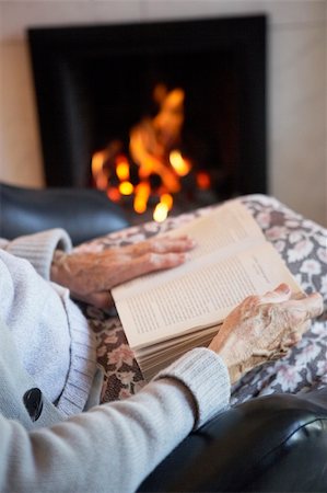 elderly woman seated in armchair - Detail Of Senior Woman Reading Book By Fire At Home Stock Photo - Budget Royalty-Free & Subscription, Code: 400-05736588