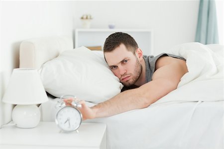 simsearch:400-04335052,k - Tired young man switching off his alarm clock in his bedroom Foto de stock - Super Valor sin royalties y Suscripción, Código: 400-05737258