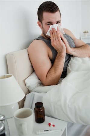 sneezing into hands - Portrait of a young man blowing his nose in his bedroom Photographie de stock - Aubaine LD & Abonnement, Code: 400-05737427