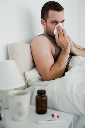 sneezing into hands - Portrait of an ill man blowing his nose in his bedroom Photographie de stock - Aubaine LD & Abonnement, Code: 400-05737428