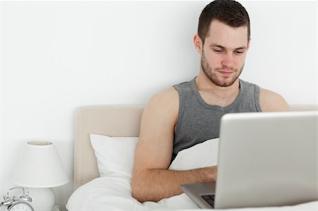 Attractive man using a laptop in his bedroom Stock Photo - Budget Royalty-Free & Subscription, Code: 400-05737439