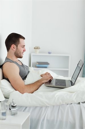 Portrait of a happy man using a laptop in his bedroom Stock Photo - Budget Royalty-Free & Subscription, Code: 400-05737444