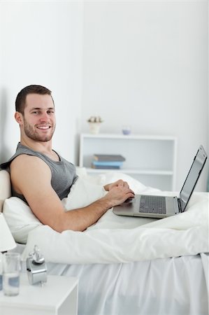 Portrait of a smiling man using a laptop in his bedroom Stock Photo - Budget Royalty-Free & Subscription, Code: 400-05737445