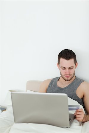 shopaholic (male) - Portrait of a young man shopping online in his bedroom Stock Photo - Budget Royalty-Free & Subscription, Code: 400-05737458