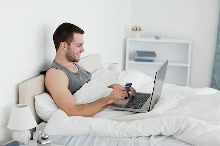 einkaufssüchtiger (männlich) - Mann in seinem Schlafzimmer Onlinekauf Stockbilder - Microstock & Abonnement, Bildnummer: 400-05737460