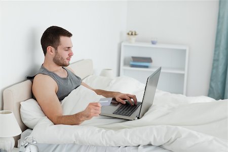 simsearch:400-05742016,k - Handsome man purchasing online in his bedroom Stock Photo - Budget Royalty-Free & Subscription, Code: 400-05737462