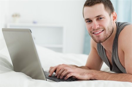 simsearch:400-05209351,k - Happy man using a laptop while lying on his belly in his bedroom Stock Photo - Budget Royalty-Free & Subscription, Code: 400-05737474