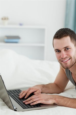 Portrait of a man using a laptop while lying on his belly in his bedroom Stock Photo - Budget Royalty-Free & Subscription, Code: 400-05737470