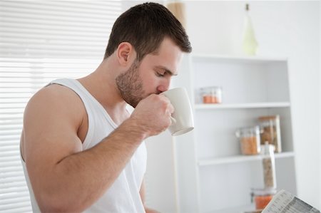 simsearch:400-05737647,k - Man drinking coffee while reading the news in his kitchen Stock Photo - Budget Royalty-Free & Subscription, Code: 400-05737574