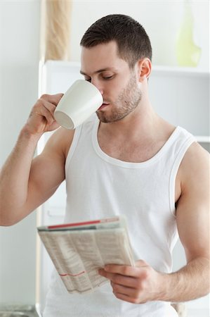 simsearch:400-05737647,k - Portrait of a young man drinking tea while reading the news in his kitchen Stock Photo - Budget Royalty-Free & Subscription, Code: 400-05737577