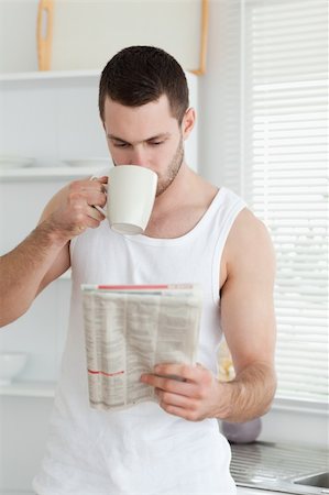 simsearch:400-05737647,k - Portrait of a man drinking tea while reading the news in his kitchen Stock Photo - Budget Royalty-Free & Subscription, Code: 400-05737571