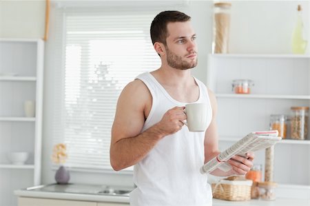 simsearch:400-05737647,k - Dreaming man drinking coffee while reading the news in his kitchen Stock Photo - Budget Royalty-Free & Subscription, Code: 400-05737588