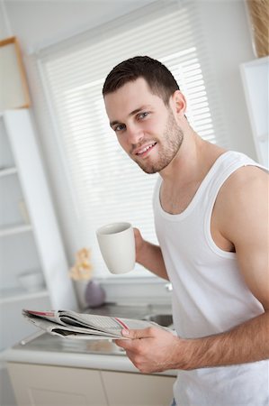 simsearch:400-05737647,k - Delighted man drinking coffee while reading the news in his kitchen Stock Photo - Budget Royalty-Free & Subscription, Code: 400-05737589