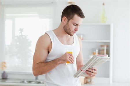 simsearch:400-05737647,k - Man drinking orange juice while reading the news in his kitchen Stock Photo - Budget Royalty-Free & Subscription, Code: 400-05737596