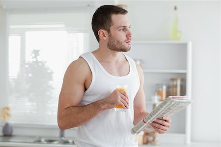 simsearch:400-05737647,k - Young man drinking orange juice while reading the news in his kitchen Stock Photo - Budget Royalty-Free & Subscription, Code: 400-05737597