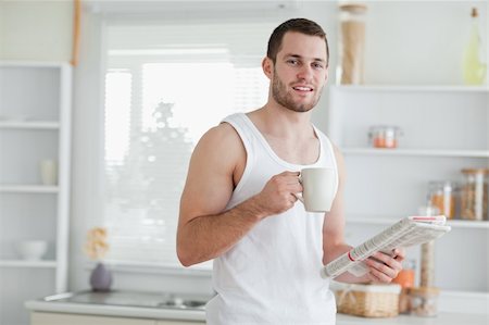 simsearch:400-05737647,k - Delighted man drinking tea while reading the news in his kitchen Stock Photo - Budget Royalty-Free & Subscription, Code: 400-05737591