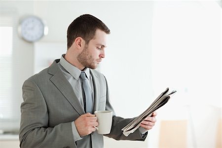 simsearch:400-05737647,k - Businessman drinking tea while reading the news in his kitchen Stock Photo - Budget Royalty-Free & Subscription, Code: 400-05737617