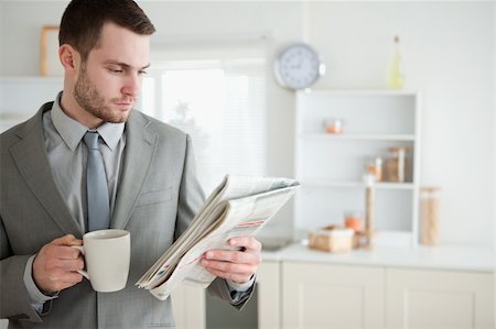 simsearch:400-05737647,k - Businessman drinking coffee while reading the news in his kitchen Stock Photo - Budget Royalty-Free & Subscription, Code: 400-05737624