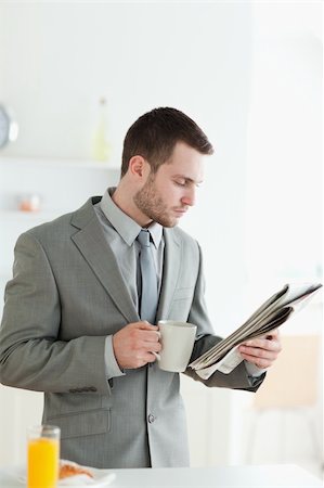 simsearch:400-05737647,k - Portrait of a handsome businessman having breakfast while reading the news in his kitchen Stock Photo - Budget Royalty-Free & Subscription, Code: 400-05737622