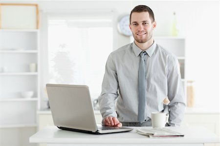 simsearch:400-05737647,k - Businessman using a laptop while drinking tea in his kitchen Stock Photo - Budget Royalty-Free & Subscription, Code: 400-05737647
