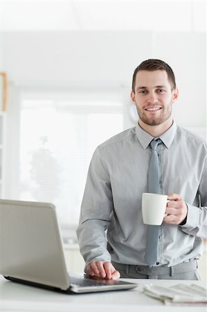simsearch:400-05737647,k - Portrait of a businessman using a notebook while drinking coffee in his kitchen Stock Photo - Budget Royalty-Free & Subscription, Code: 400-05737651