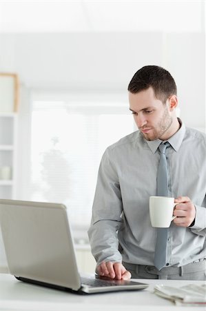 simsearch:400-05737647,k - Portrait of a businessman using a notebook while drinking tea in his kitchen Stock Photo - Budget Royalty-Free & Subscription, Code: 400-05737652