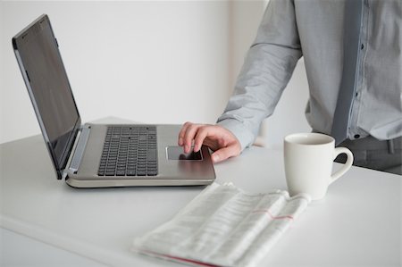 simsearch:400-05737647,k - Businessman using a laptop with a cup of tea and a newspaper in his kitchen Stock Photo - Budget Royalty-Free & Subscription, Code: 400-05737653