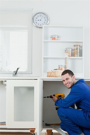 simsearch:400-05201869,k - Portrait of a smiling handyman fixing a door in a kitchen Foto de stock - Super Valor sin royalties y Suscripción, Código: 400-05737675